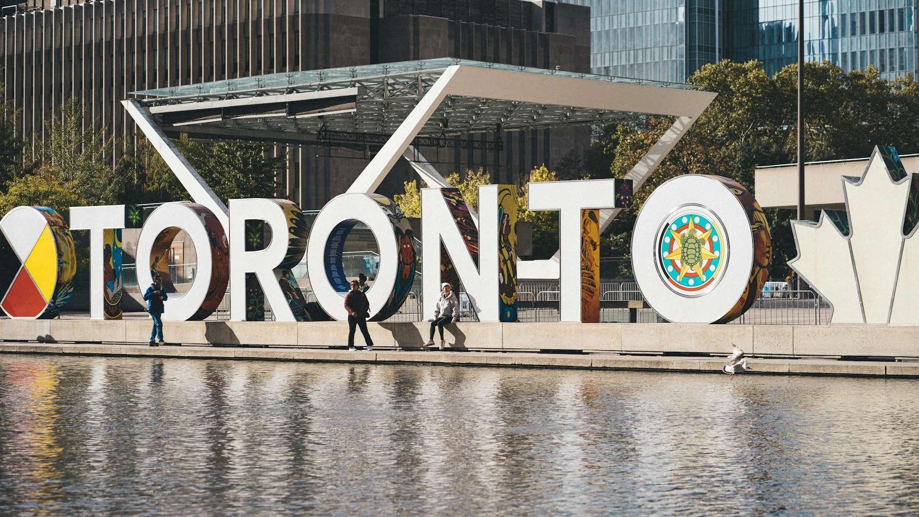 Iconic Toronto sign with people walking by, a popular tourist attraction in downtown Toronto.
